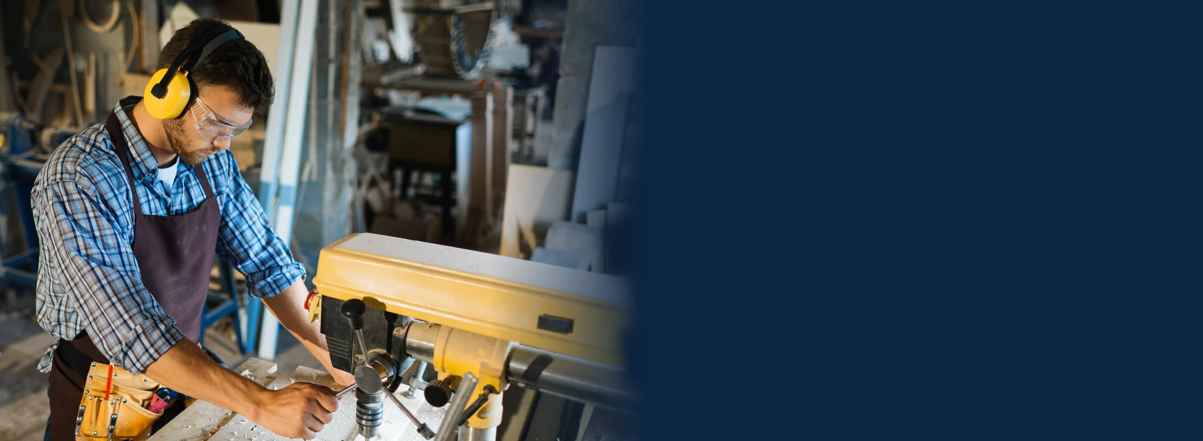 Carpenter operating a drill press in a timber workshop